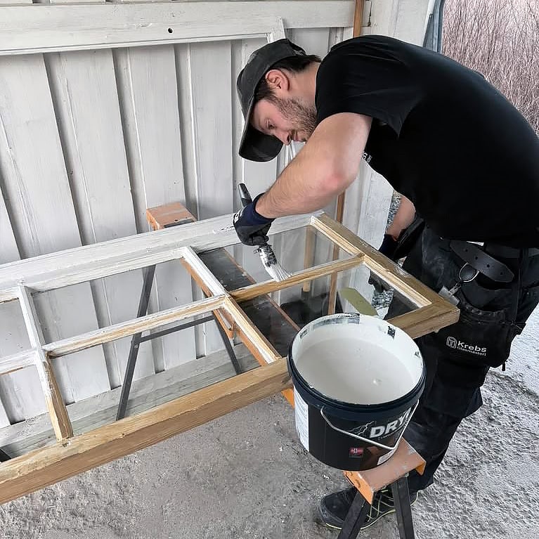 En glasmästare målar ett fönster